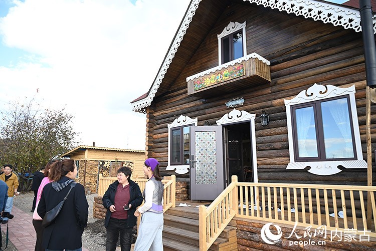“油画小屋”外，姜心（右一）正在与当地居民聊天。人民网记者 刘艺琳摄