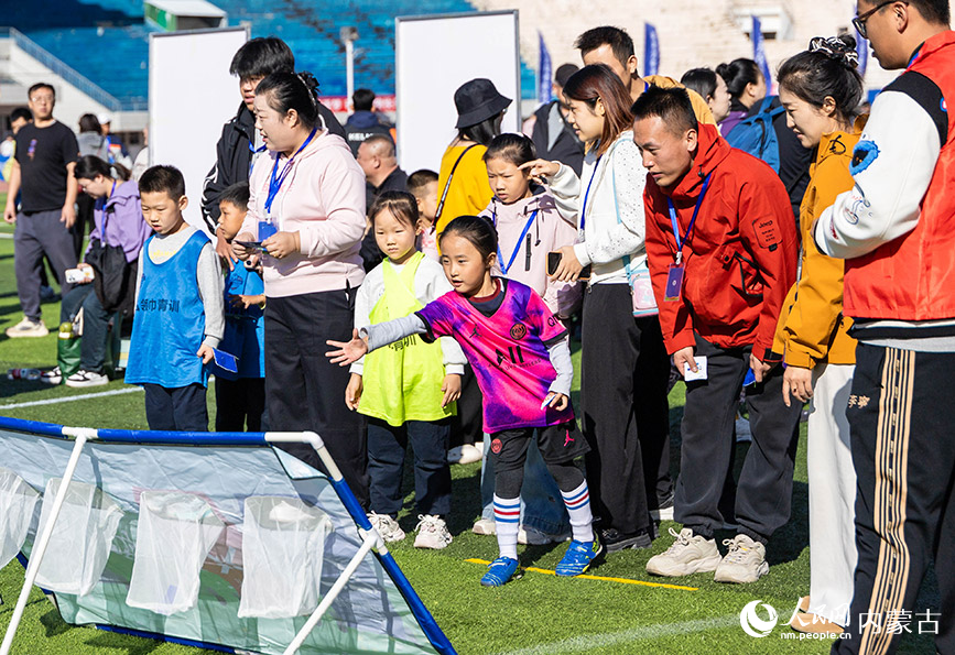 10月11日,呼和浩特市幼儿足球嘉年华暨低年龄段校园足球比赛现场,孩子们在参与足球趣味闯关游戏。丁根厚摄