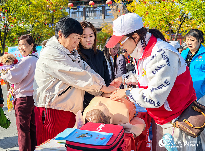 呼和浩特市玉泉區“我們的節日·重陽”主題活動現場，紅十字會工作人員在指導老年人學習心肺復蘇急救技能。丁根厚攝