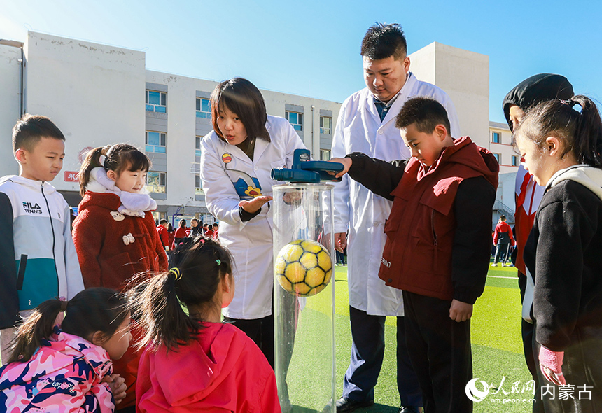 呼和浩特市玉泉區石東路小學校園科學節活動現場，學生在體驗“隱形大力士”科學實驗秀。丁根厚攝